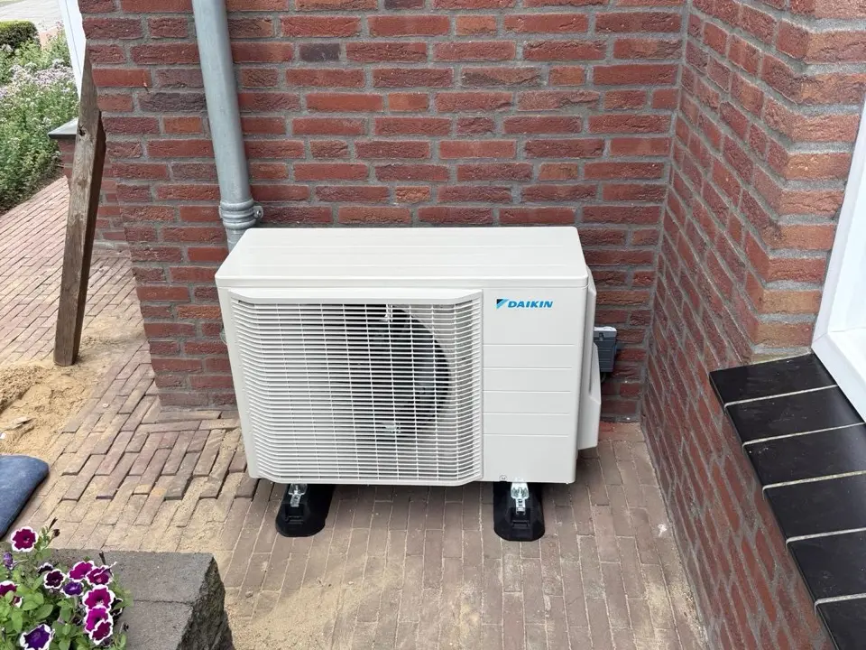 Daikin-buitenunit op trillingsdempers naast een terras