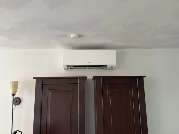 Daikin-binnendeel boven twee houten kasten