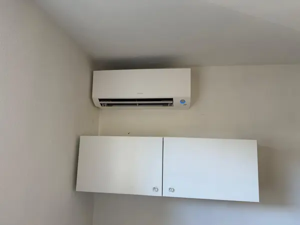 Wit Daikin airco-binnendeel boven witte wandkastjes