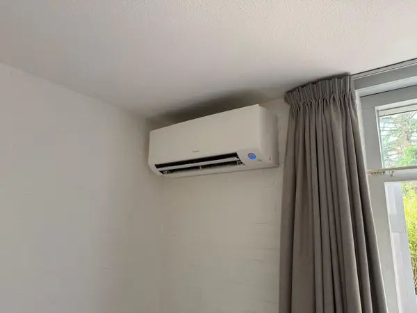 Daikin-binnendeel in de hoek naast een gordijn