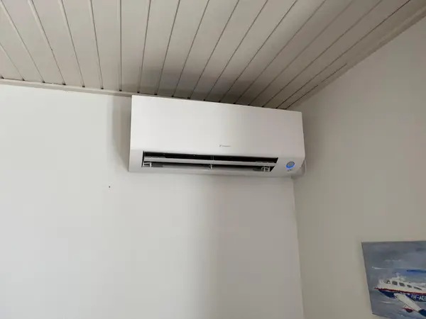 Wit Daikin airco-binnendeel onder een houten schrootjesplafond