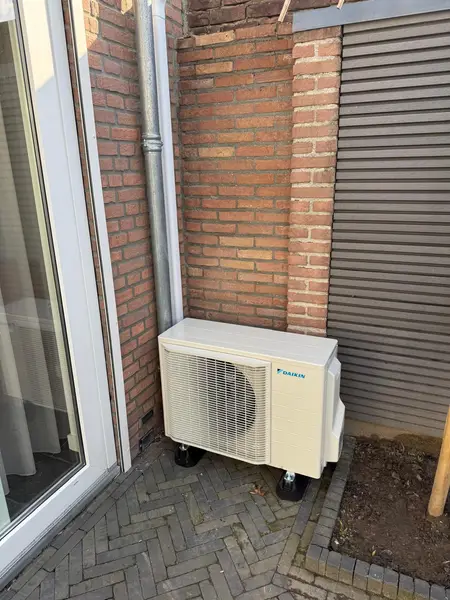Daikin-buitenunit in de hoek van een bakstenen gevel
