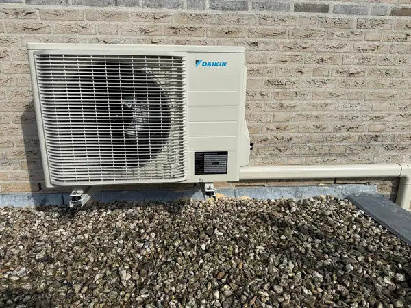 Daikin-buitenunit op beugels boven een grinddak