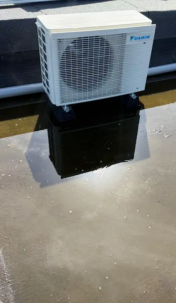 Daikin-buitenunit op dempers op een nat plat dak