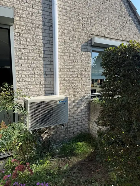 Daikin-buitenunit op wandbeugels tegen een lichte gevel