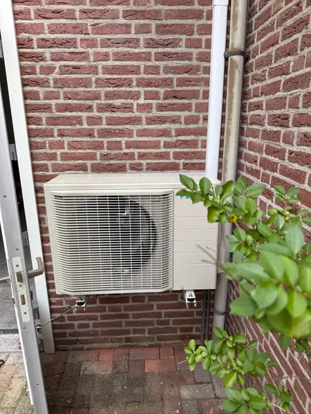 Daikin-buitenunit op wandbeugels tegen rode baksteen